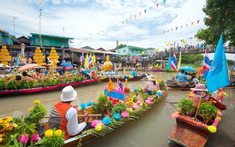 Colorful boats filled with goods and vendors float along the canal at Damnoen Saduak Floating Market in Thailand