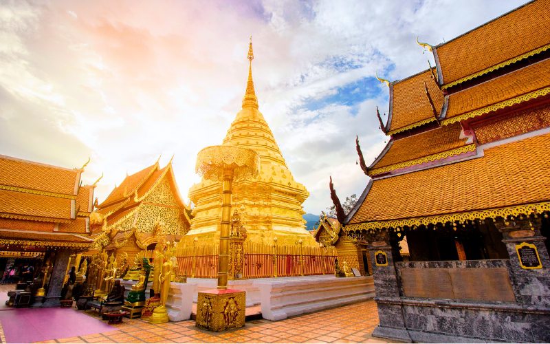 Golden chedi of Wat Phra That Doi Suthep temple in Chiang Mai, Thailand, glowing under sunset sky with ornate Lanna architecture