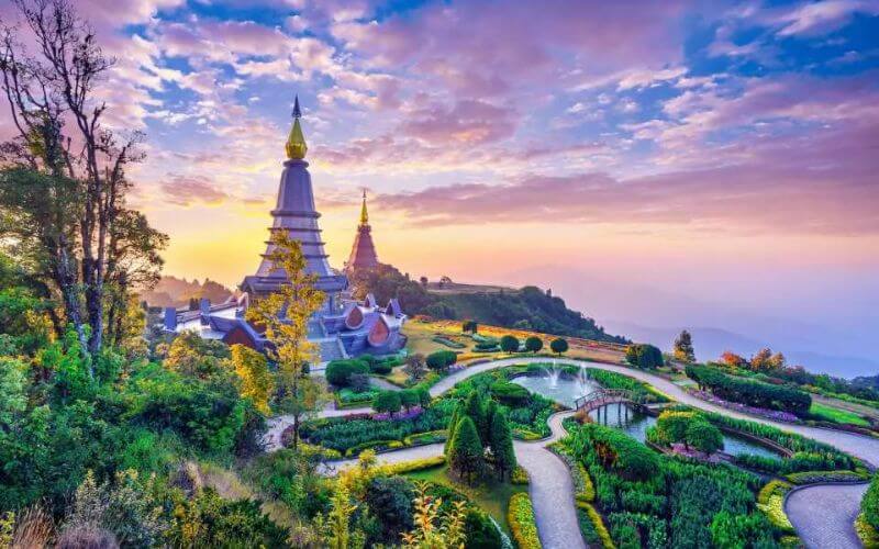 Twin pagodas at Doi Inthanon, Chiang Mai, Thailand, surrounded by vibrant gardens under a colorful sunrise sky
