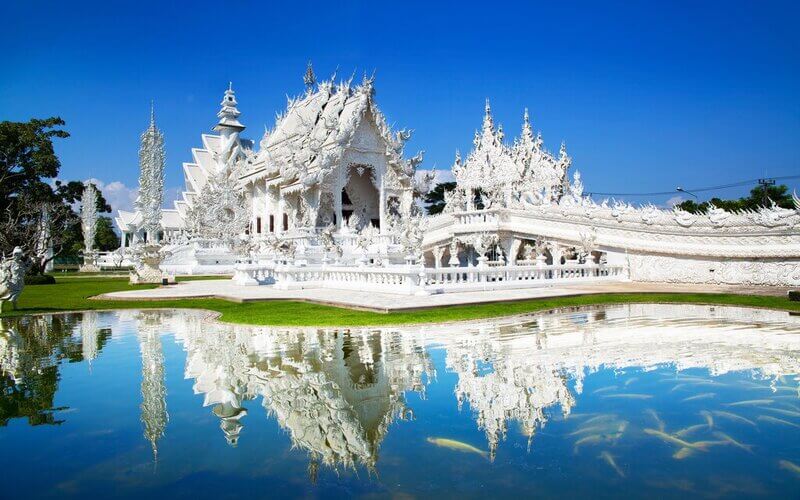 White Temple in Chiang Rai, stands out with its pure white color and exquisite details, reflected on the lake surface.